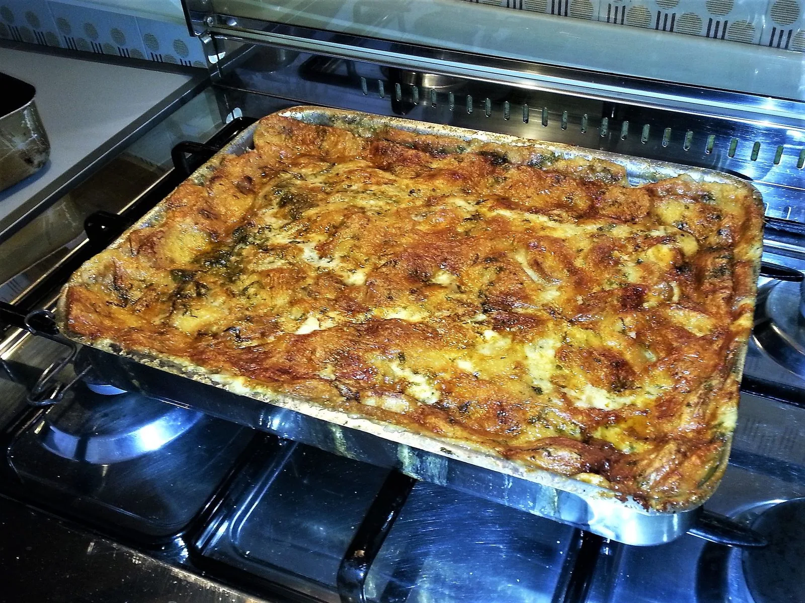 Teglia di zuppa gallurese appena sfornata, con la crosta dorata di formaggio ed erbe aromatiche